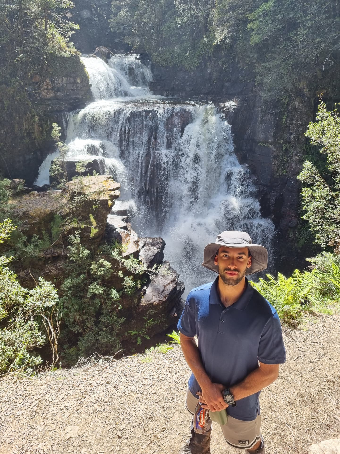 A Southbound outdoor educator standing in front of a Tasmanian waterfall